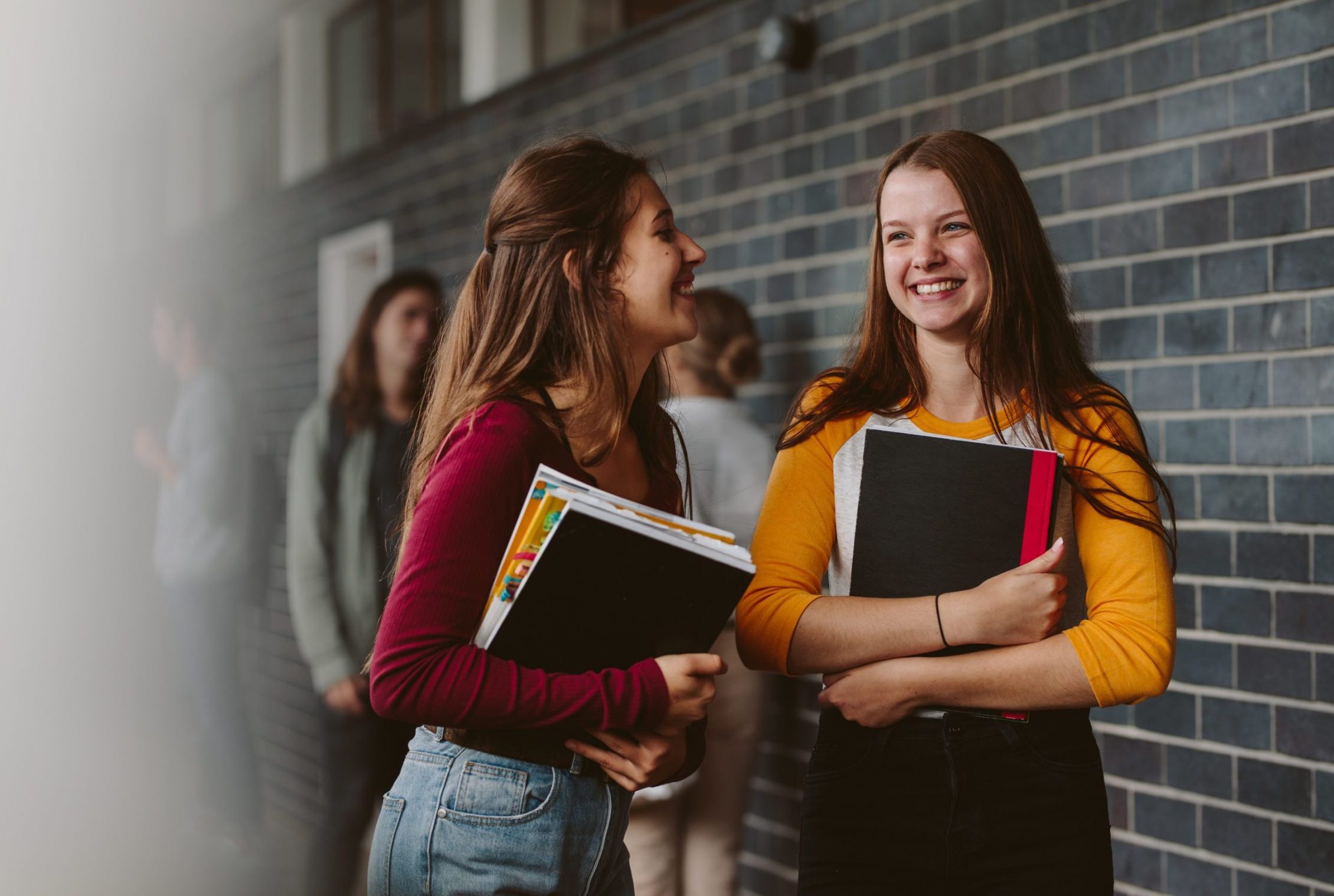 Portrait of smiling girls walking through high school corridor after their class. Two female college students after lecture.